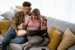 Young couple watching movie on lap top. Loving couple enjoying at home. Top Movies of 2023