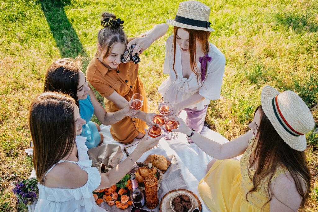 Galentines day upper ivy apartments Slumber party. Summer Picnic Party Ideas, Outdoor Gathering with friends. Young women girl friends drinking wine, laughing, having fun together at picnic.